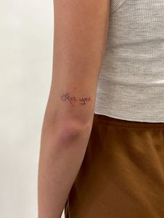 a woman's arm with the word love you tattooed on her left arm, in cursive font