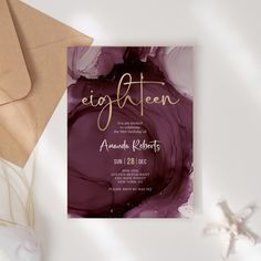 an elegant purple and gold wedding card with the word eighteen on it, surrounded by seashells