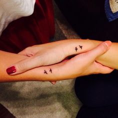 two people with matching tattoos on their arms, one is holding the other's hand