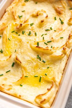 a casserole dish filled with potatoes and topped with green onion sprinkles