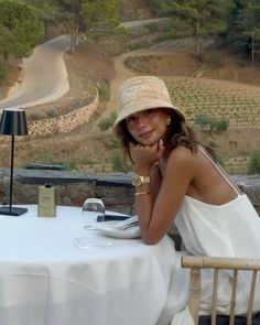 a woman sitting at a table with a hat on