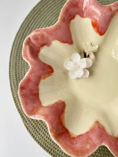 a pink and white flower sitting on top of a plate