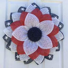 a red white and blue burluck wreath hanging on the front door with stars