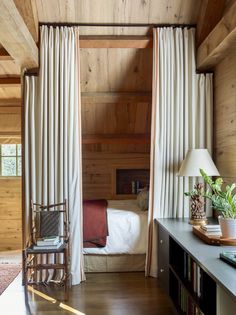 a bedroom with wood paneling and white drapes hanging from the ceiling next to a bed