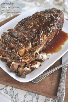 a piece of meat sitting on top of a white plate next to a knife and fork