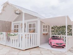 a pink toy car is parked in front of a small white house with a porch