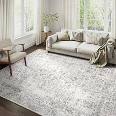 a living room with a couch, chair and rug on the floor in front of two windows