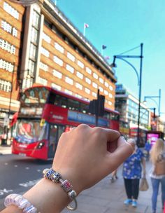 a woman is holding her hand up in the air near a double - decker bus