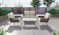 an outdoor patio furniture set on a deck with trees and bushes in the back ground