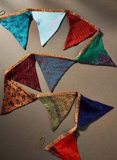 several different colored kites hanging from strings on a wall in the shape of an ornament