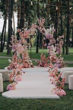 an outdoor ceremony setup with flowers and candles on the ground, surrounded by trees in the background