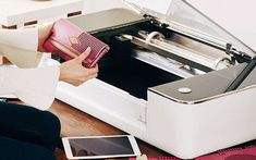 a woman is holding a pink box in front of a printer