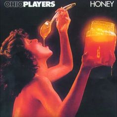 a woman drinking from a glass next to a honey jar with a spoon in it