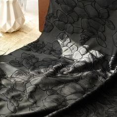 a black and white flowered fabric on a table with vases in the background