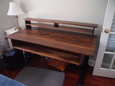 a wooden desk sitting on top of a hard wood floor next to a lamp and door