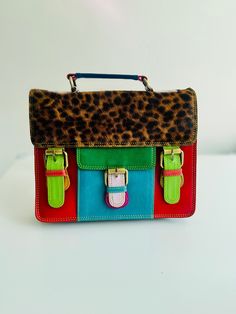 Make a bold statement with our Sustainable Statement Piece: Recycled Leather Crossbody Satchel Bag. This unique bag, handcrafted from colourful recycled leather, is a perfect way to add a touch of personality to your outfit.  Each bag is one-of-a-kind, a beautiful testament to artisanal creation. Makes a perfect gift for any occasion! Birthdays, Mother's Day, Christmas, graduations, or just because - this versatile clutch is sure to be cherished. 🌟 Spacious and functional: Featuring multiple co Vintage Multicolor Satchel With Leather Handles, Multicolor Satchel With Leather Handles For Daily Use, Multicolor Satchel With Detachable Strap For Daily Use, Retro Multicolor Satchel With Adjustable Strap, Multicolor Retro Satchel With Adjustable Strap, Multicolor Satchel For Everyday Use, Multicolor Shoulder Bag With Detachable Strap For School, Multicolor Leather Handle Shoulder Satchel, Retro Multicolor Satchel For Everyday Use