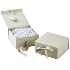 an open box with ribbon and paper in it on a white surface, next to the opened box