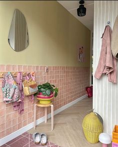 a pink tiled hallway with two stools and mirrors hanging on the wall next to it