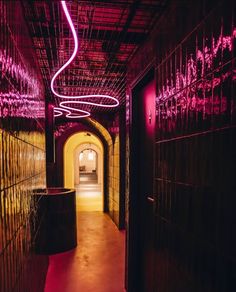 the tunnel is lit up with pink light and purple lighting on the ceiling, along with black walls