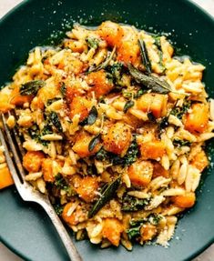 a plate filled with pasta and vegetables on top of a table next to a fork