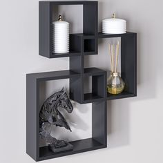 a black shelf with some white vases and candles on it's sides in front of a gray wall