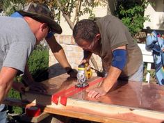 two men are working on a table with some glue and wood planks in front of them