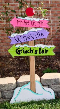 a wooden sign sitting on top of a lush green grass covered park bench next to a brick wall