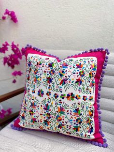 a decorative pillow with pom - poms on top of it sitting on a chair