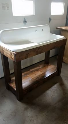 a large white sink sitting on top of a wooden stand in a bathroom next to a window