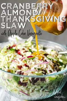 a person pouring dressing into a glass bowl filled with coleslaw and apple cider