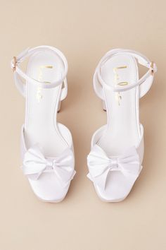 Your walk down the aisle just got even more fabulous, thanks to the Lulus Pearlla Bow White Satin Platform High Heel Sandals! These sleek satin heels feature a trendy square toe upper (atop a 1"" toe platform), and a wide toe strap adorned with a darling bow detail. Matching straps sprout from the sides to wrap and secure around the ankle with a gold buckle, all atop a sky-high block heel that is sure to take your look to the next level! 4. 5" wrapped block heel. Cushioned insole. Felted rubber Square Toe Sandals For Summer Wedding, Summer Wedding Sandals With Square Toe, Summer Wedding Square Toe Sandals, Low Heel Satin Sandals For Spring, Formal Low Heel Sandals With Satin Bow, Square Toe Sandals For Wedding In Spring, Summer Evening Wedding Shoes In Satin, Satin Wedding Shoes For Summer Evening, Party Sandals With Bow And Square Toe