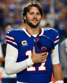 a close up of a football player holding a ball in his hand and looking at the camera