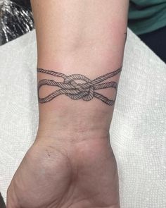 a person's wrist with a tattoo on it that has a knot in the middle