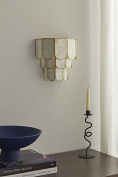 a blue bowl sitting on top of a wooden table next to a book and candle