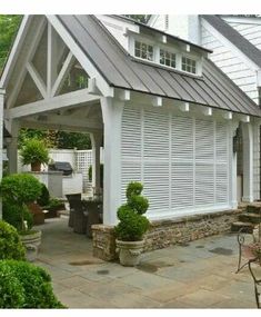 a house with white shutters and stone patio