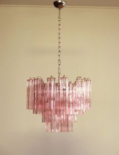 a pink chandelier hanging from the ceiling in a room with beige walls and flooring