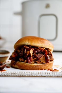 a pulled pork sandwich sitting on top of a white plate next to an instant pot