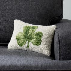 a pillow with a four leaf clover on it sitting on a couch next to a chair