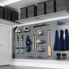 an organized garage with sports equipment on the wall and storage bins in front of it