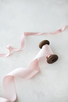 pink ribbon and two wooden buttons on a white surface