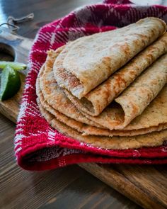 a stack of tortillas sitting on top of a wooden cutting board