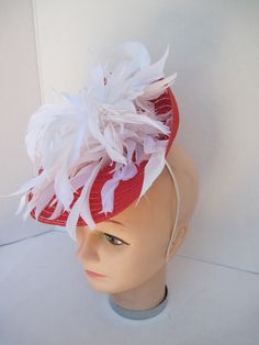 "* Red and White always looks so fresh and clean and this one is designed with lots of white spiky feathers that catch the breeze giving a feminine flair to the fascinator. * The hat form is about 12\" folded in back and tilted in a sophisticated design. * It is light weight, balanced and comfortable to wear year round. * Designed on a metal headband, it fits just about any head size and when viewed from any direction it looks complete, striking and eye catching. * Wear it throughout the year fo White Adjustable Fascinator With Feather Trim, White Fascinator With Feather Trim And Adjustable Fit, White Fascinator With Feather Trim, White Feather Trim Hat For Kentucky Derby, White Hats With Feather Trim For Races, Red Feathered Fascinator For Kentucky Derby, White Ostrich Feather Hat For Kentucky Derby, White Summer Hat With Feather Trim, White Summer Hat With Feathers