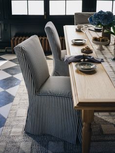 a dining room table with striped chairs and plates on it