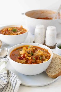 two bowls of soup with bread on the side