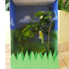 an open box with a green plant and a bird in the tree on it's side