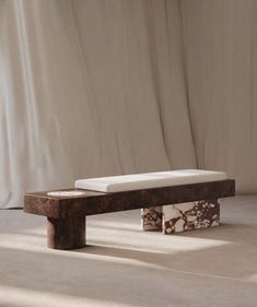 a wooden bench sitting on top of a white floor next to a curtained wall