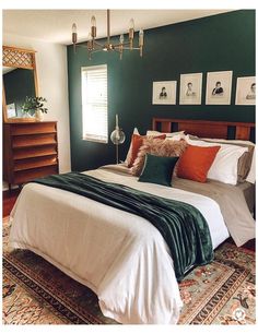 a large bed in a bedroom with green walls and pictures on the wall above it