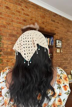 the back of a woman's head wearing a crochet hat with flowers on it