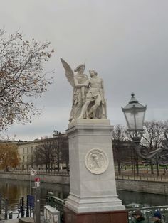 a statue in the middle of a park next to a river