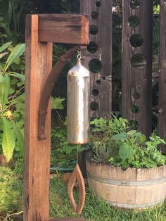 an old metal water bottle hanging from a wooden trellis next to a potted plant